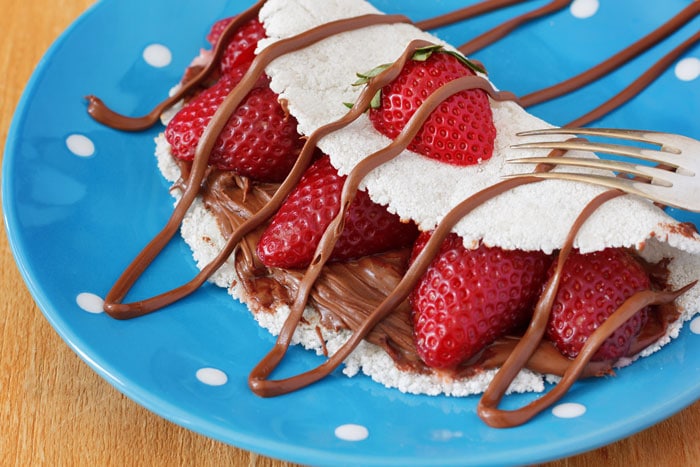 Beiju or tapioca filled with strawberry and chocolate on a blue plate