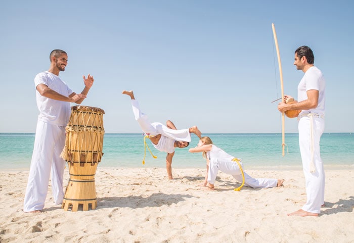 Friends training capoeira on the beach, fun activities to do in Brazil