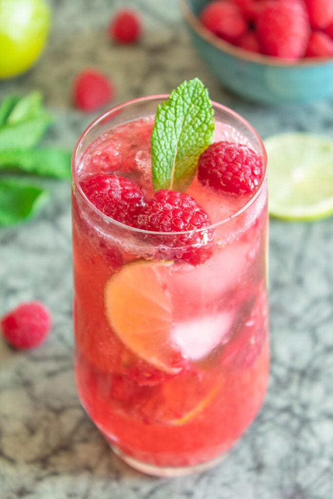 Raspberry caipiroska surrounded by raspberries and lime