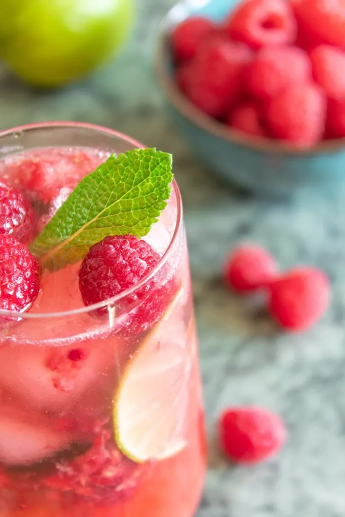 Raspberry caipiroska surrounded by raspberries and lime