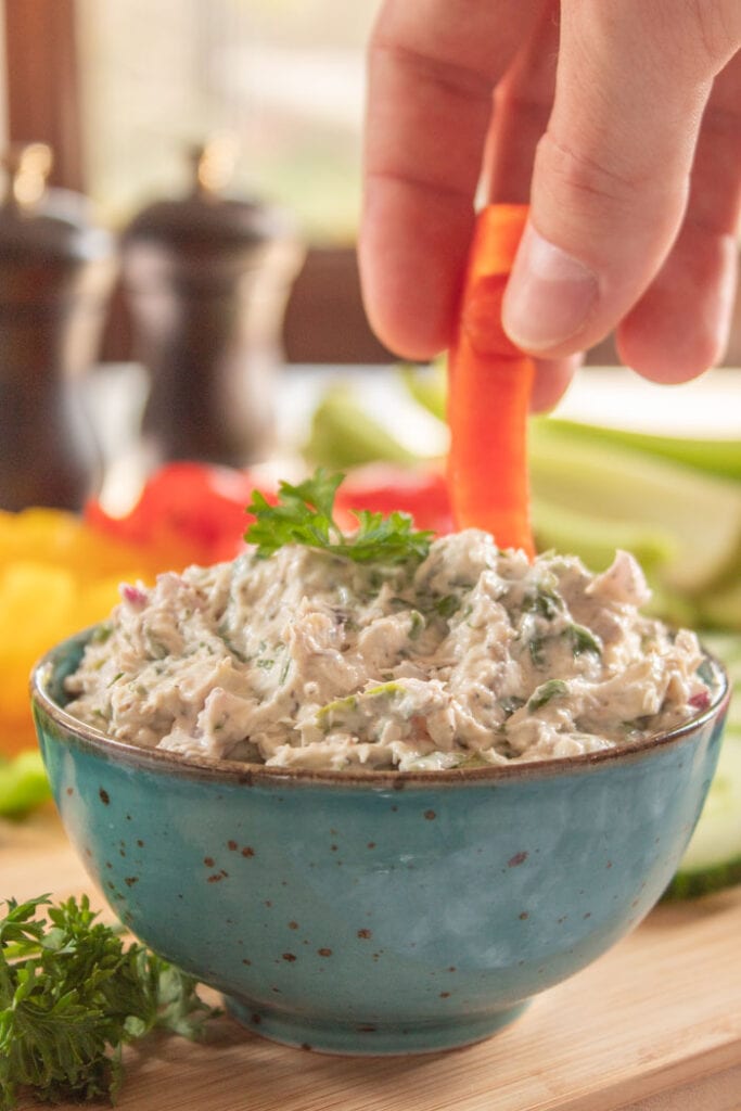Hand dipping vegetable into sardine dip